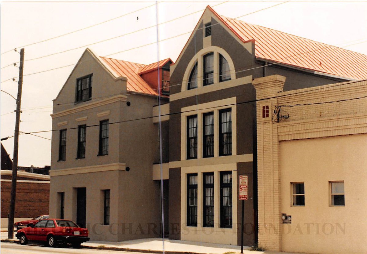 A two-story building with a red roof and cars parked in front.
